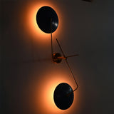 Two-light blue disc wall sconce with E26 holders, solid brass construction, and soft ambient backlit illumination