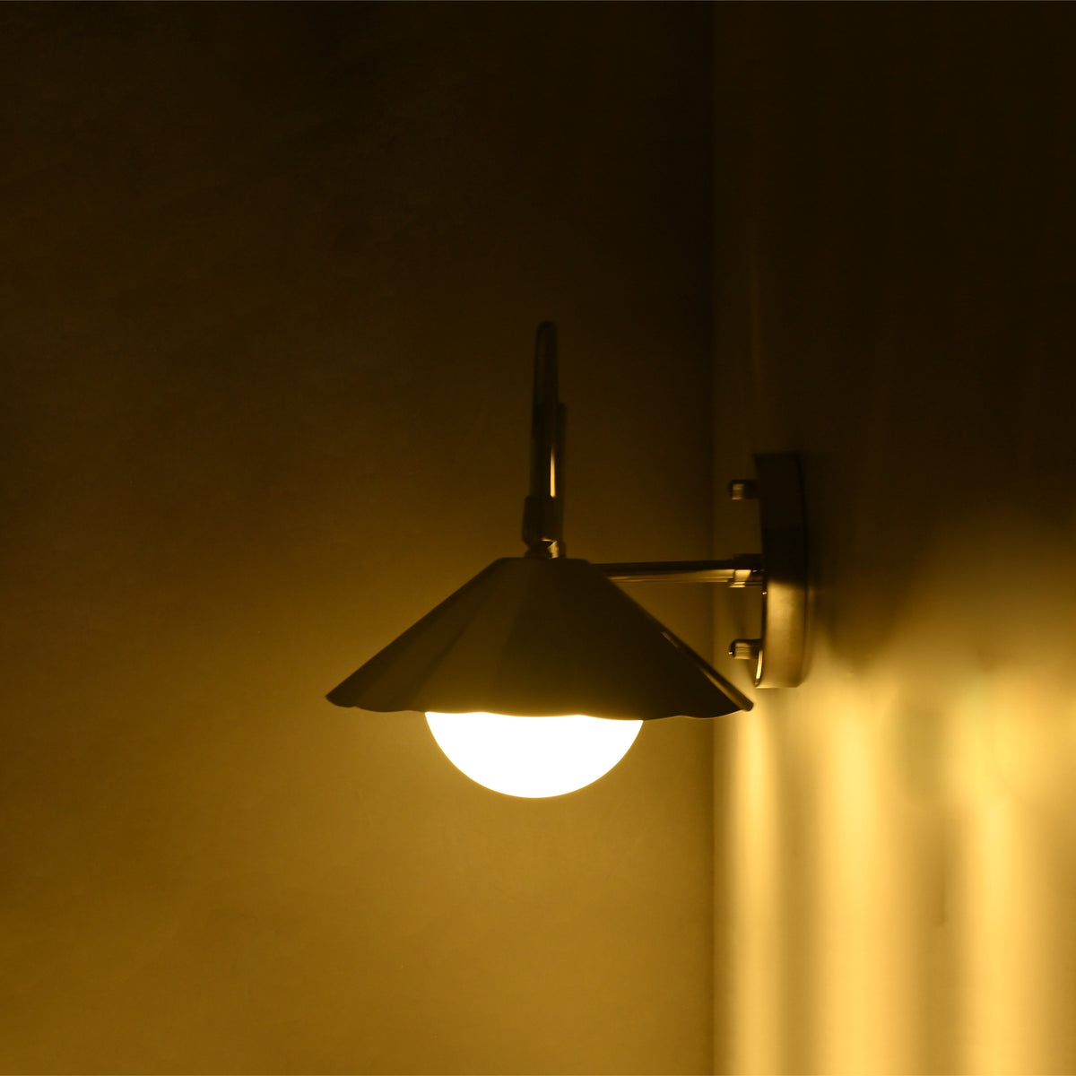 Side profile of the Aurora modern polished nickel wall sconce highlighting the fluted metal shade, frosted globe diffuser, curved arm, and round wall backplate.