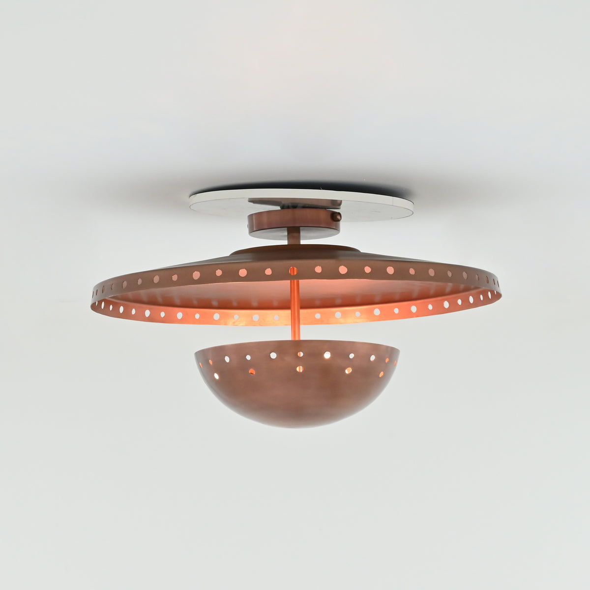 Illuminated Valencia copper ceiling light casting warm patterned shadows through decorative perforations