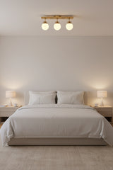 Valencia linear globe ceiling light featuring three round glass shades and solid brass ceiling plate