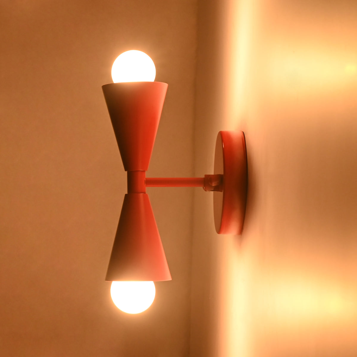 Mid century red wall sconce shown from side with straight arm and round wall backplate