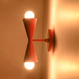 Mid century red wall sconce shown from side with straight arm and round wall backplate