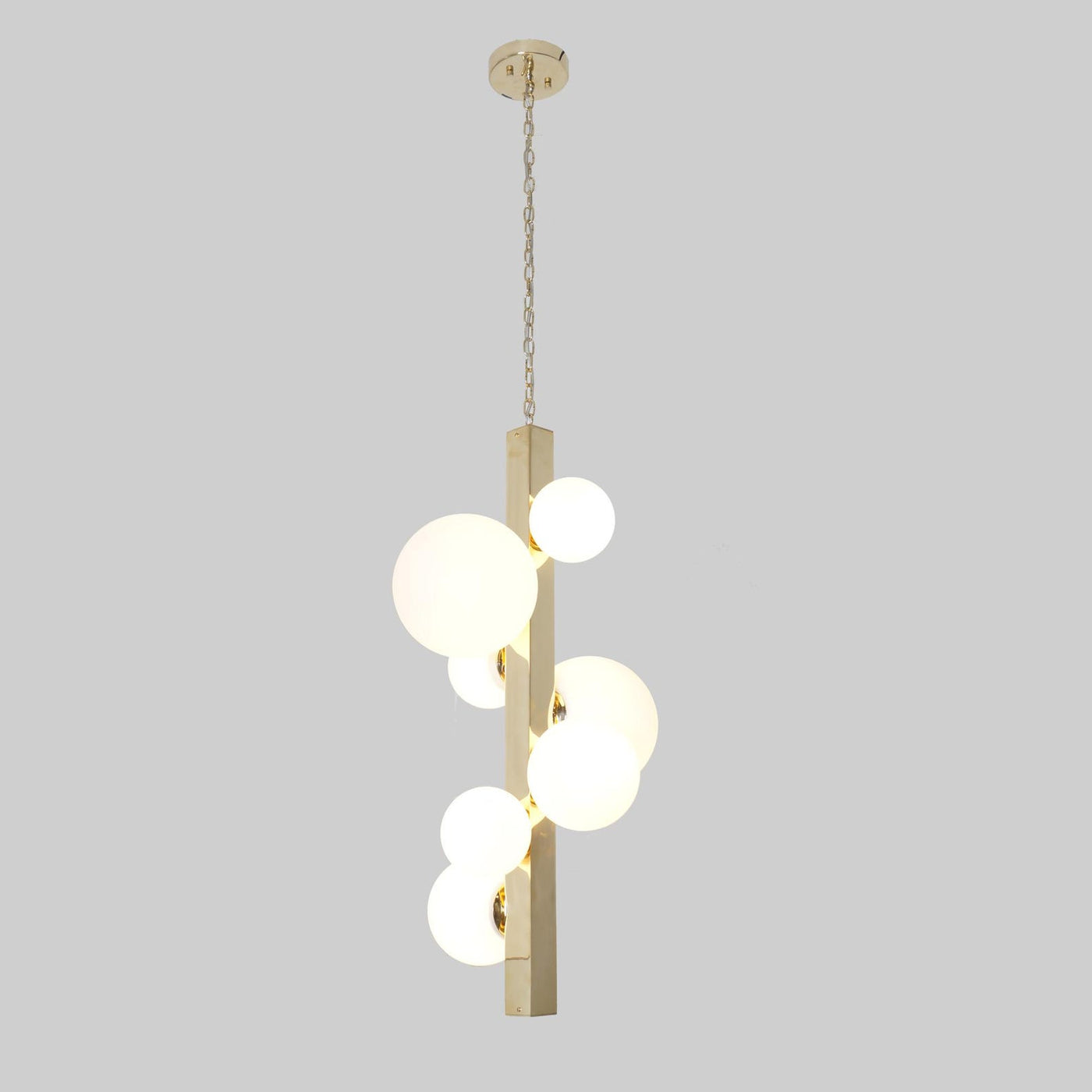 Vertical brass chandelier with frosted glass globes suspended on chain, handmade by Brass Leaf Studio.