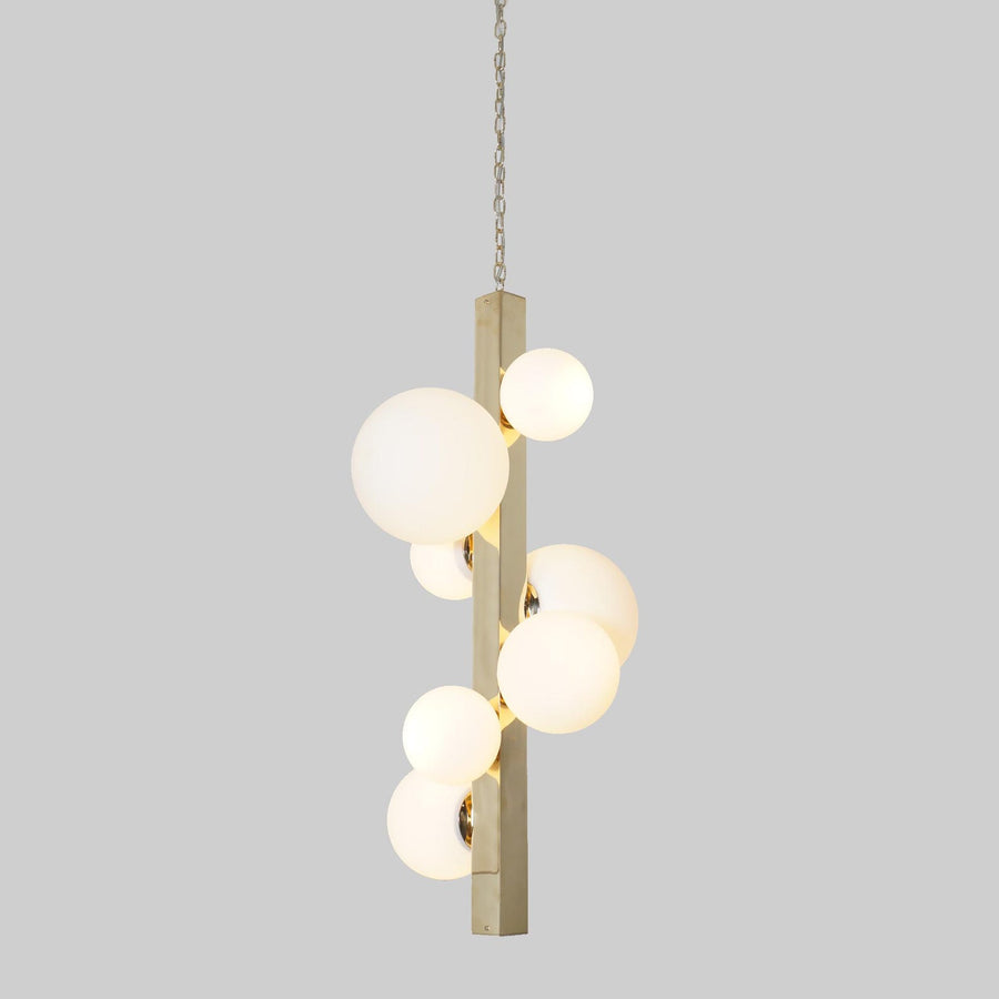 Vertical brass chandelier with frosted glass globes suspended on chain, handmade by Brass Leaf Studio.