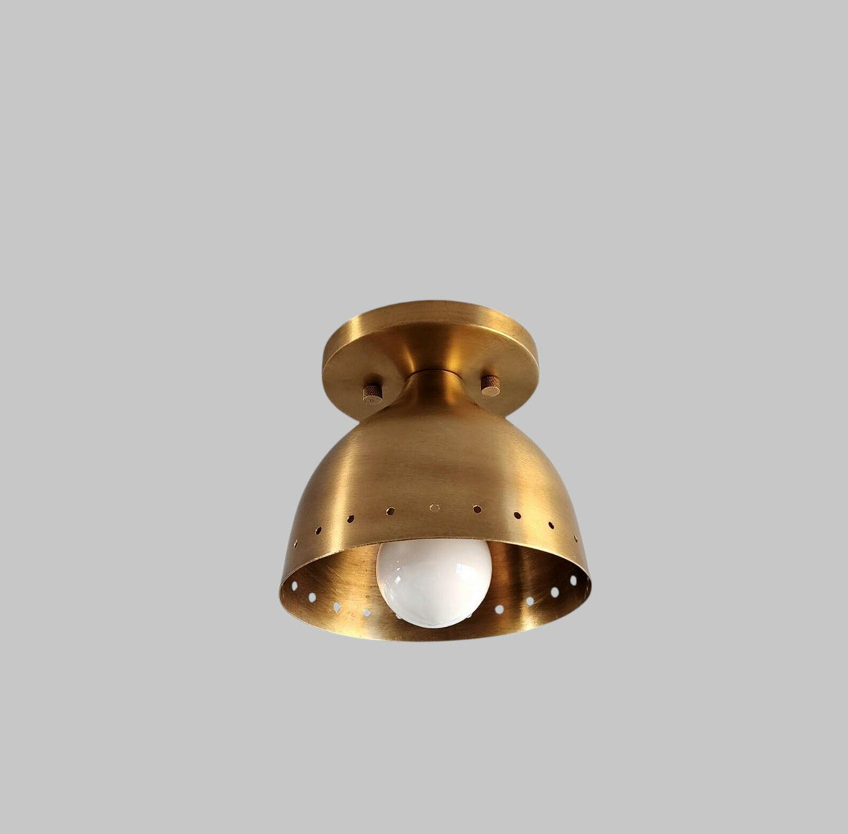 Angled view of vintage brass flush mount light with smooth bowl shade and warm brushed brass finish