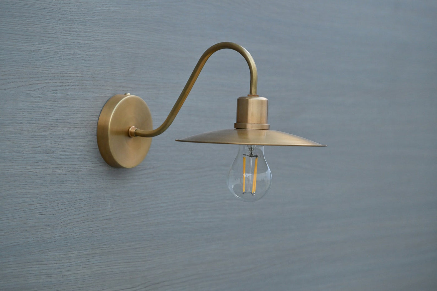 Side view of vintage brass gooseneck wall light with exposed bulb, handmade by Brass Leaf Studio in brushed satin brass finish
