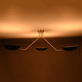 Night view of black and brass chandelier emitting soft golden ambient light across the ceiling.