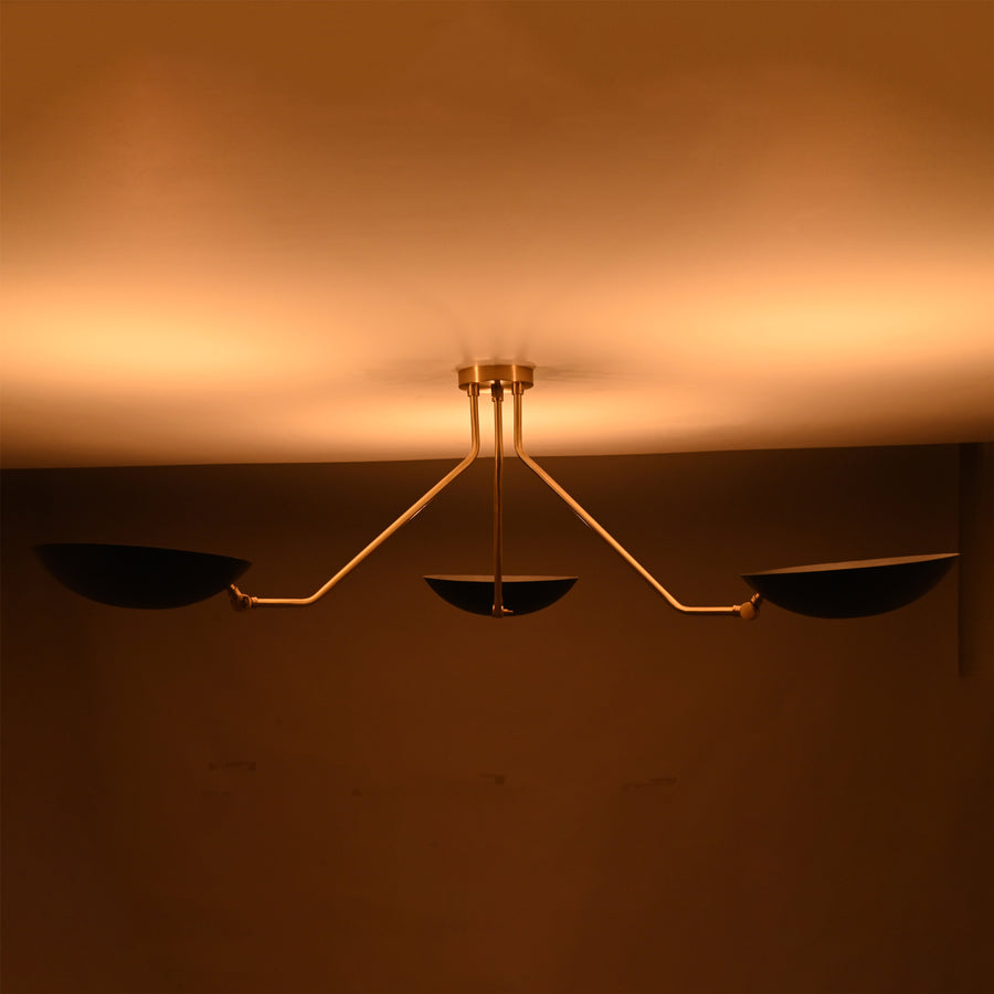 Front view of modern black and brass 3-light bowl chandelier with sculptural arms and matte black shades.