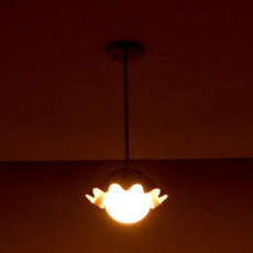 Handmade brass ruffled pendant lamp with globe bulb casting warm ambient glow in dark space