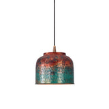 Copper drum pendant light switched on, creating a warm downward glow from the textured inner shade