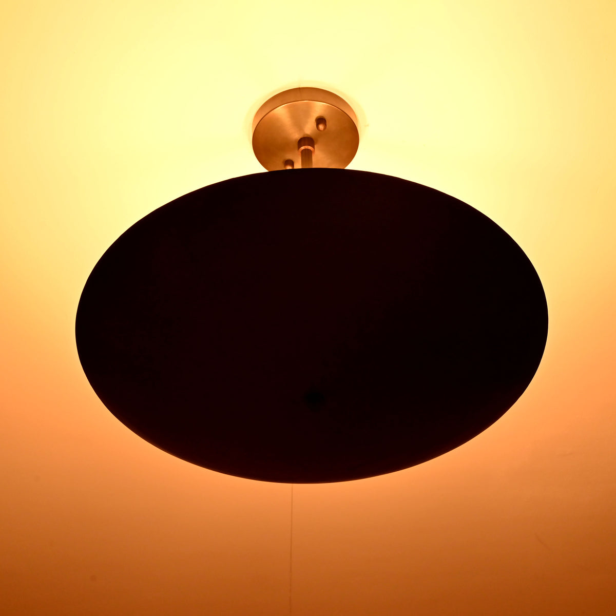 5-light blackened brass ceiling fixture glowing with warm indirect uplighting